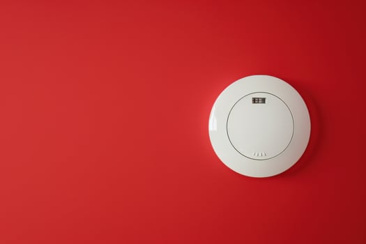 Circular smoke detector mounted on a vibrant red wall in a modern interior space photo