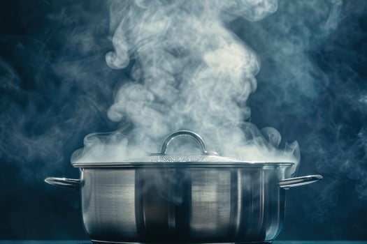 Steam rising from a covered pot on the stove in a modern kitchen photo