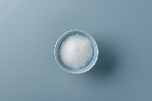 Bowl of granulated sugar on a blue surface photo