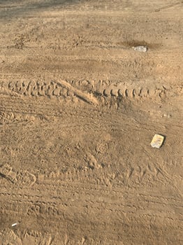 Highway construction track featuring a dirt road with truck wheel marks and workers' shoe prints. Ideal for construction and infrastructure visuals. photo