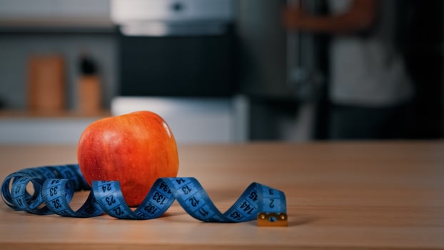 Red apple and tape measure on kitchen table unrecognizable blurred African man athlete opening fridge searching ingredients for lunch eating cooking dinner food fridge meal dieting sport nutrition photo