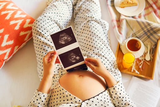 Pregnant woman with book, tea, cake relaxing at home. Top view photo