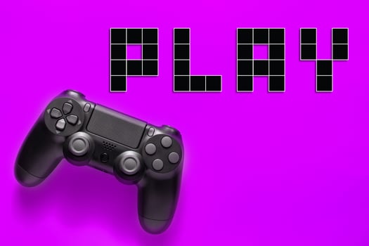 Black modern gamepad and word play on a colored background . Gaming concept photo