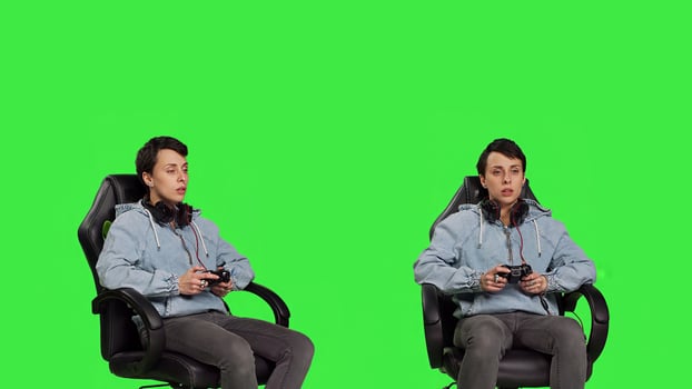 Woman gamer playing online games with controller, sitting in an office chair against greenscreen backdrop. Joyful person having fun with e sport competition, modern gaming setup. Camera B. photo