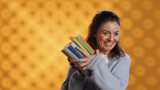 Excited woman delighted about books ordered, treasuring them, isolated over studio background. Euphoric reading enthusiast cherishing stack of novels, feeling lively and overjoyed, camera A photo