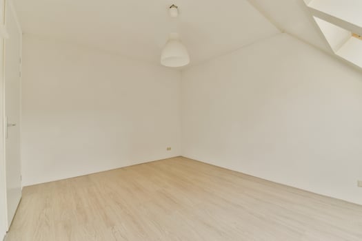 An empty room with a white wall and wooden floors photo