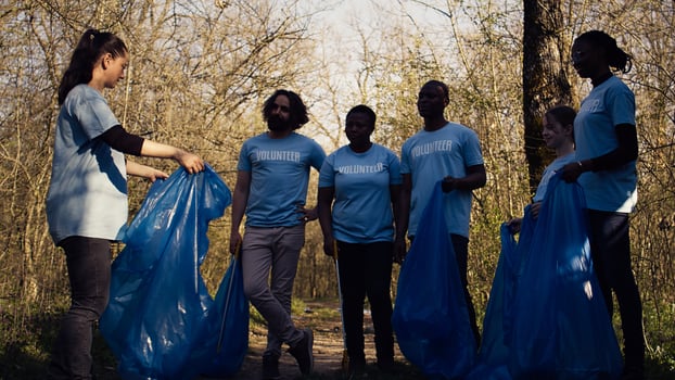 Volunteers group preparing to collect rubbish and junk from the woods, recycling plastic waste and other trash in bags. Environmental activists protecting the nature by picking up garbage. Camera B. photo