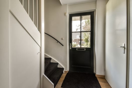 A hallway with a black door and stairs photo
