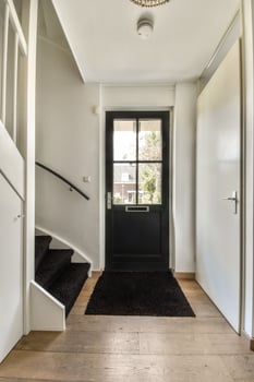 A hallway with a black door and stairs photo