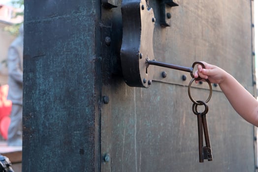 a small child's hand tries to open a padlock with a large key photo