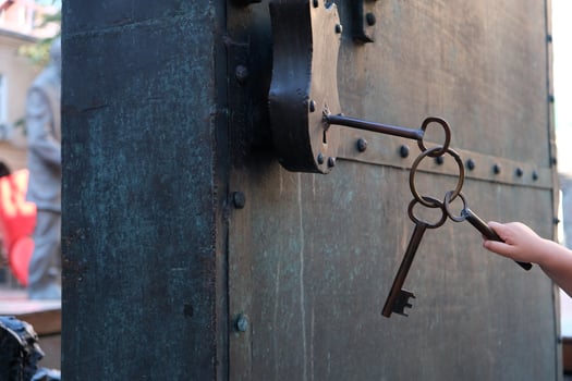 a small child's hand tries to open a padlock with a large key photo