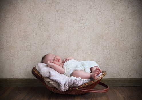 Baby sleeping in the basket on the wooden floor photo