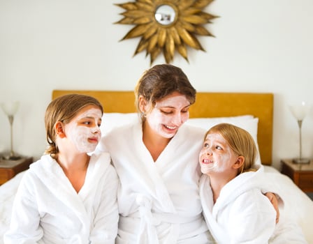 Happy mother and girls in bathrobes with cream mask photo