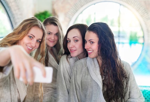 Young women relaxing in the spa resort doing selfy wearing toweling robes photo