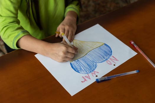 Children's hands of a child draw a heart-shaped icon with the image of the National Flag of Ukraine. View from above. Children against war. Children's drawing for peace in Ukraine photo