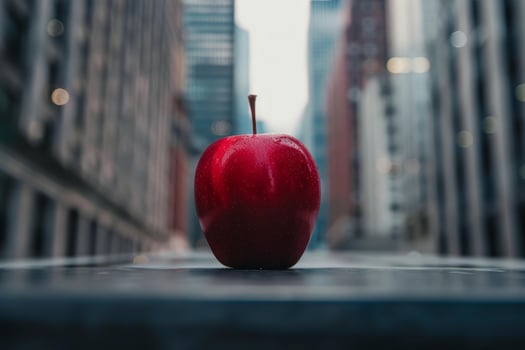Red apple standing on a ledge with cityscape in background photo