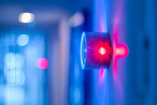 Red security alarm light flashing on wall in hallway photo