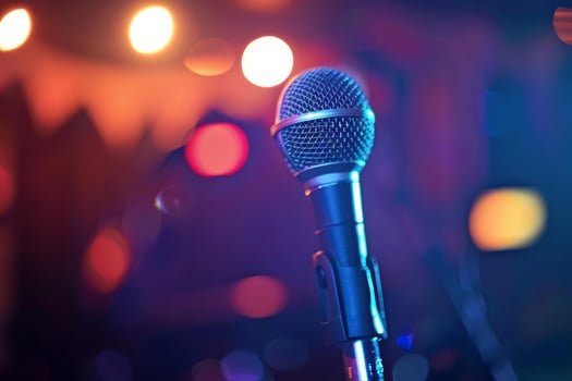 Microphone standing on stage with blurred colorful stage lights in background photo