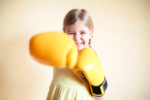 Little girl with yellow boxing gloves over yellow wall background photo
