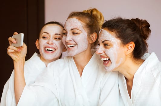 Three young happy women with face masks at spa resort. Frenship and wellbeing concept photo