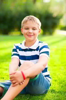 Little boy sitting on the grass with smile photo
