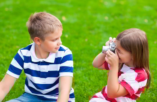 Pretty little brother and sister playing with a camera in summer park photo