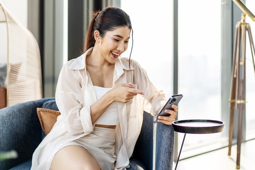 Smiling asian woman hold use smart phone sitting at home. watching social media. Portrait, entertainment, communication, work or study, connection, mobile apps, lifestyle concept. photo
