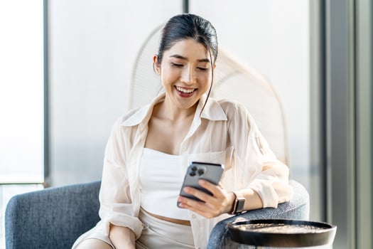 Smiling asian woman hold use smart phone sitting at home. watching social media. Portrait, entertainment, communication, work or study, connection, mobile apps, lifestyle concept. photo