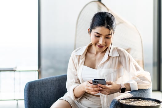 Smiling asian woman hold use smart phone sitting at home. watching social media. Portrait, entertainment, communication, work or study, connection, mobile apps, lifestyle concept. photo