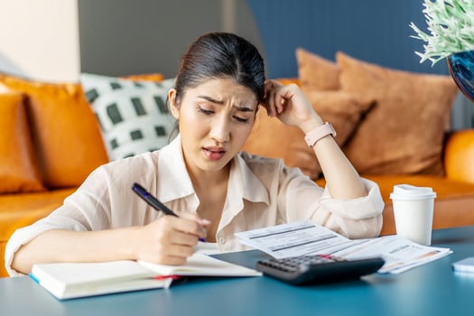 Upset asian woman sit at desk do accounting job or manage personal finances, reviewing bills feels upset due huge taxes, sum need to pay, experiences lack of money, crisis, bankruptcy concept photo