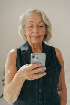 A Senior Woman Fully Engaged and Interacting with Her Smartphone in a Modern Setting photo