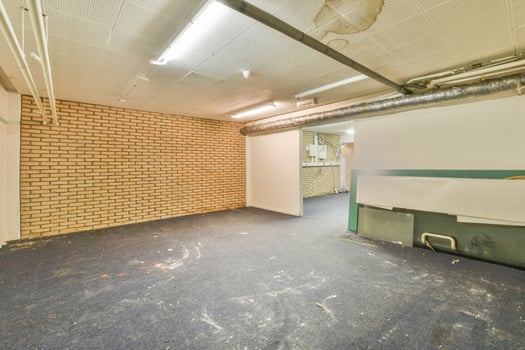 A large empty room with a brick wall and a blue floor photo