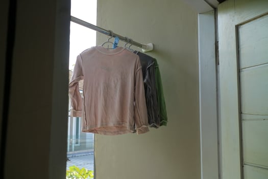 Several long sleeve children's t-shirts are drying on the balcony of the house during the day photo