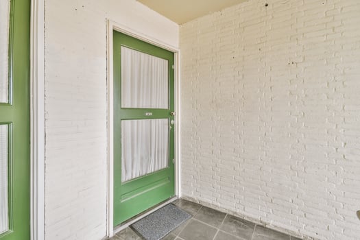 A white brick wall with green doors and a green tile floor photo