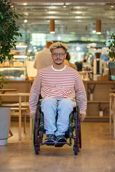 Calm man with disability in wheelchair moves around coffeeshop. Accessible environment for everyone. photo