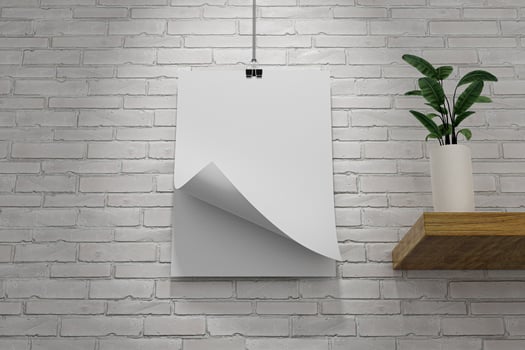 A white poster hanging on a brick wall with one corner flipped over photo