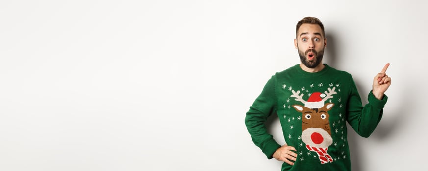 Winter holidays and christmas. Man looking excited as pointing finger right at logo, standing amazed against white background photo