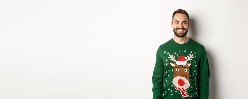 New Year party and winter holidays concept. Happy bearded man in funny christmas sweater standing against white background photo