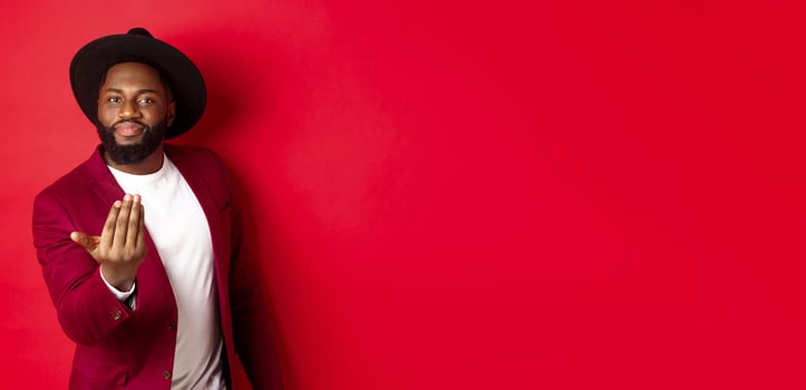 Handsome and masculine Black man asking come closer, luring to step forward, calling for you, standing over red background photo