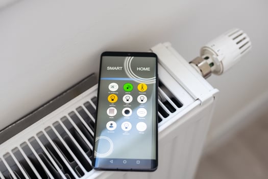 Smartphone with launched application for air temperature adjustment opposite the radiator. Health microclimate at home concept photo