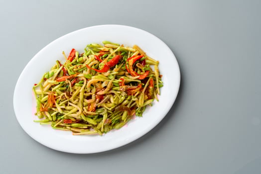 Tumis Bunga Pepaya ikan teri is Indonesian traditional food. stir fry Papaya's buds and flower with fried anchovy Served on white plate and isolated on gray background. photo