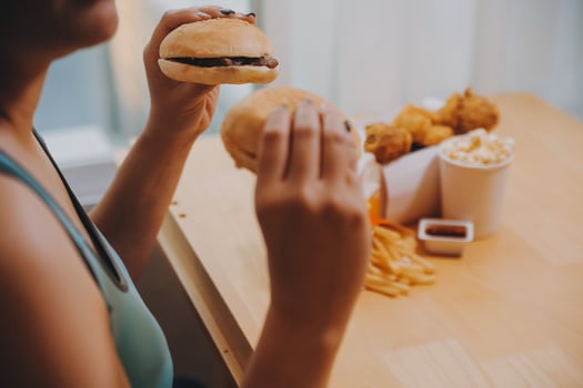 Binge eating disorder concept with woman eating fast food burger, fired chicken , donuts and desserts photo