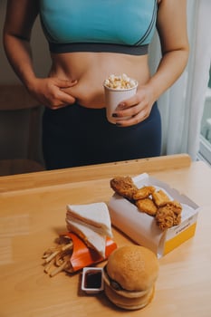 To eat or not. Cheerless plump woman looking at the burger while thinking to eat it or not photo