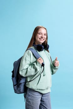 Happy woman smiling, doing thumbs up hand gesturing, showing approval, having positive mood. Jolly person presenting confirmation, doing agreement finger sign, studio background photo