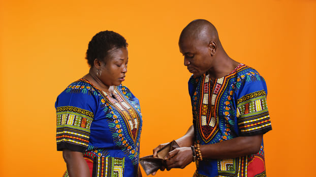 Ethnic couple fighting over being broke in studio, young man opening empty wallet and getting frustrated about bankruptcy. African american woman yelling at her husband, deep in debt. photo