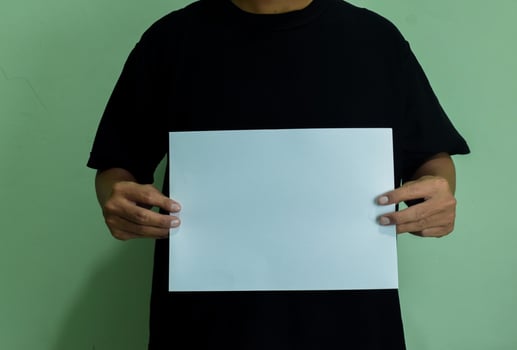 A man holding a blank piece of paper in horizontal orintaion. Mockup of person with statement or message photo