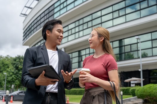 A positive Asian businessman is briefing his assistant on work while walking outdoors. photo