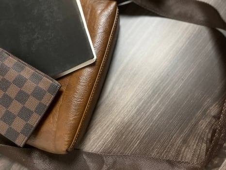 Leather bag with gadgets and notebooks on Wooden Work Desk photo