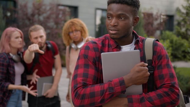 Students multiracial classmates mock humiliate bully mockery at college university outdoors discriminate showing thumbs down African American lonely man student stressed guy education studying problem photo
