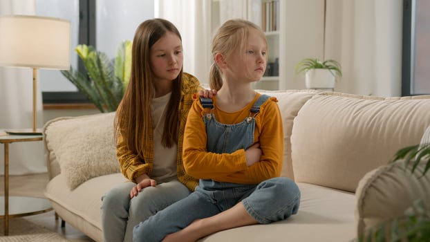Upset angry little Caucasian children girls sisters kids friends quarrel daughters apology ask for forgiveness feeling guilty touch calming down offended ignore family argument problems at home couch photo